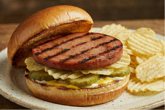 Sandwich with a thick slice of bologna, mustard, and pickles on a toasted brioche bun