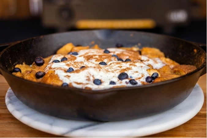 Golden brown Blueberry French Toast in a cast iron skillet, topped with fresh blueberries.