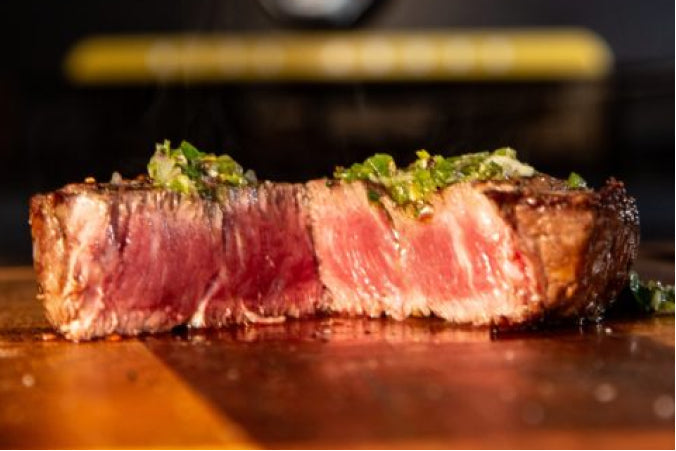 A thick, juicy filet mignon seared to a golden-brown crus, served medium rare and topped with a vibrant green chimichurri sauce