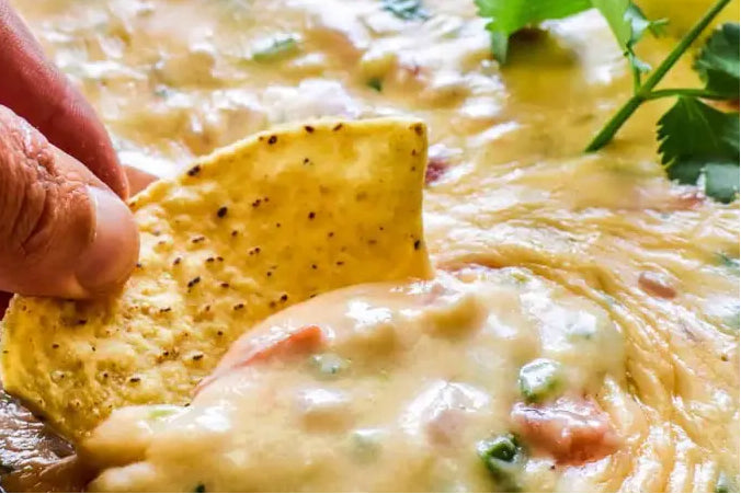 A bubbling bowl of creamy Chorizo Queso dip featuring a blend of melted jalapeño Velveeta, queso blanco, and Monterrey jack cheese, stirred with savory cooked chorizo and colorful diced sweet peppers