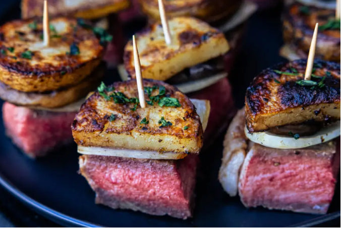 Gourmet Steak & Potato Kebites featuring cubes of tender medium-rare smoked steak topped with a slice of onion, mushroom, and a golden-brown seasoned potato slice