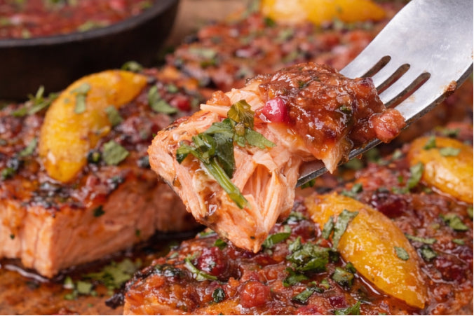 Grilled salmon steaks topped with a vibrant peach and raspberry glaze and chopped mint