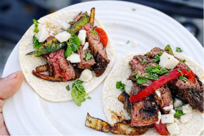 Juicy grilled steak tacos topped with fresh cilantro, diced onions, and  served on soft corn tortillas