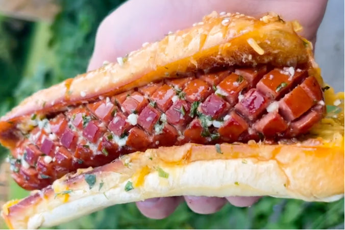 Grilled cheese hot dog featuring a cross-hatched jumbo beef frank tucked into a toasted garlic butter bun with melted cheese and herbs