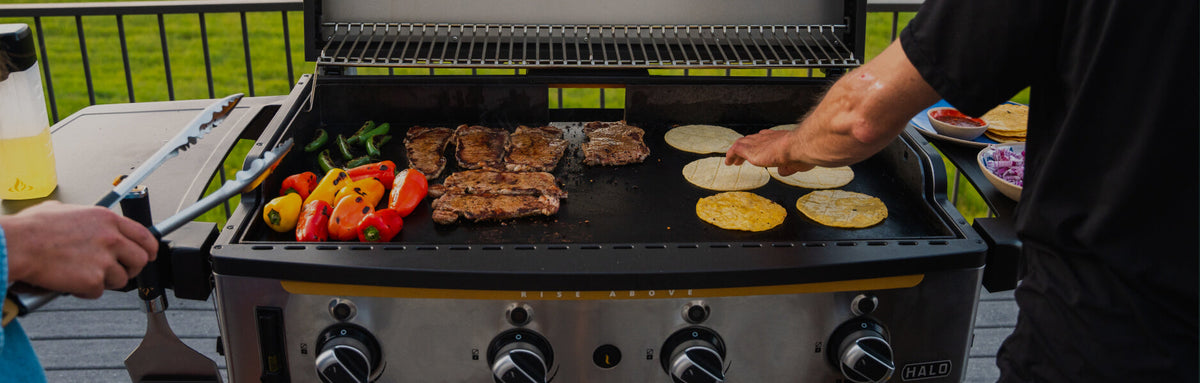 Two men using the HALO Elite4B to cook tortillas, peppers, and steaks.
