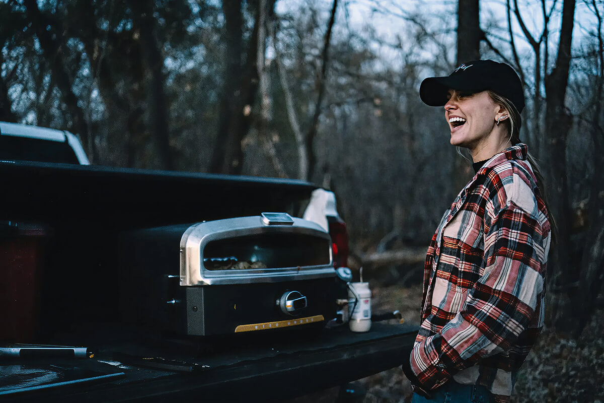 A woman using the Versa 16 Pizza Oven from the back of her truck.