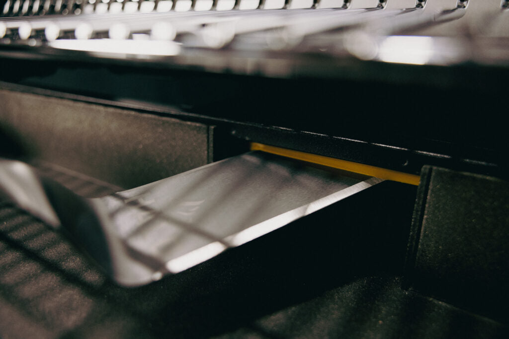 Detail shot of the integrated stainless steel drip tray being positioned for efficient cleanup.