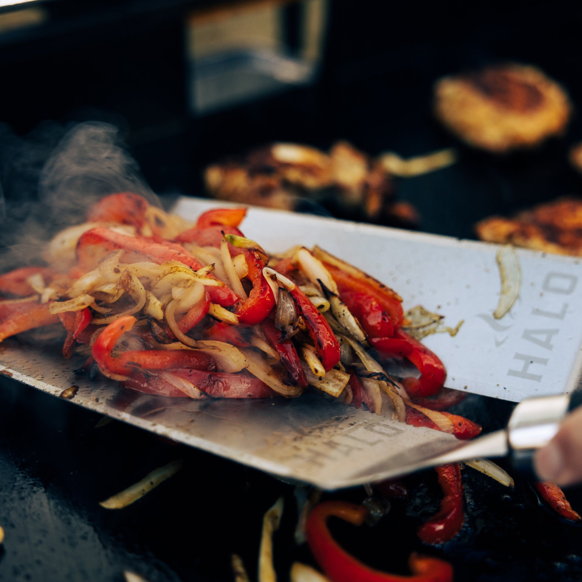 Grilled vegetables on a metal spatula with 'HALO' branding over a grill.