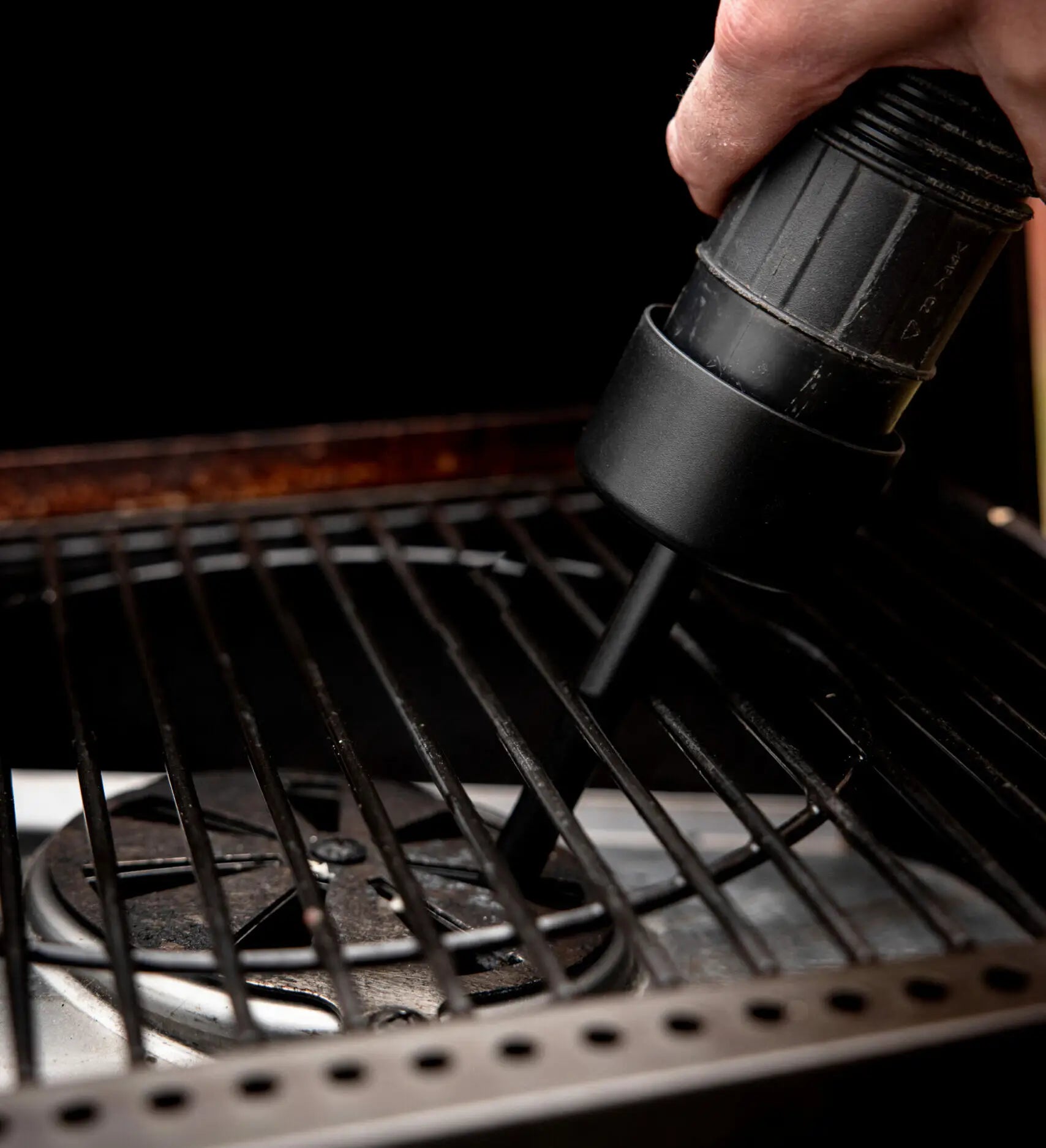 Close-up of the HALO Burn Pot Attachment being used to vacuum ash directly from the pellet grill

