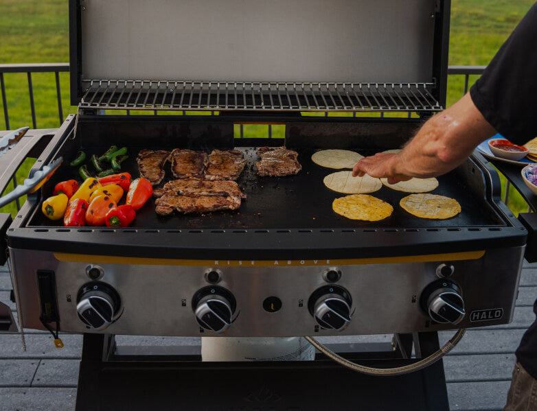 Two people grilling vegetables and meat on the halo elite4B griddle