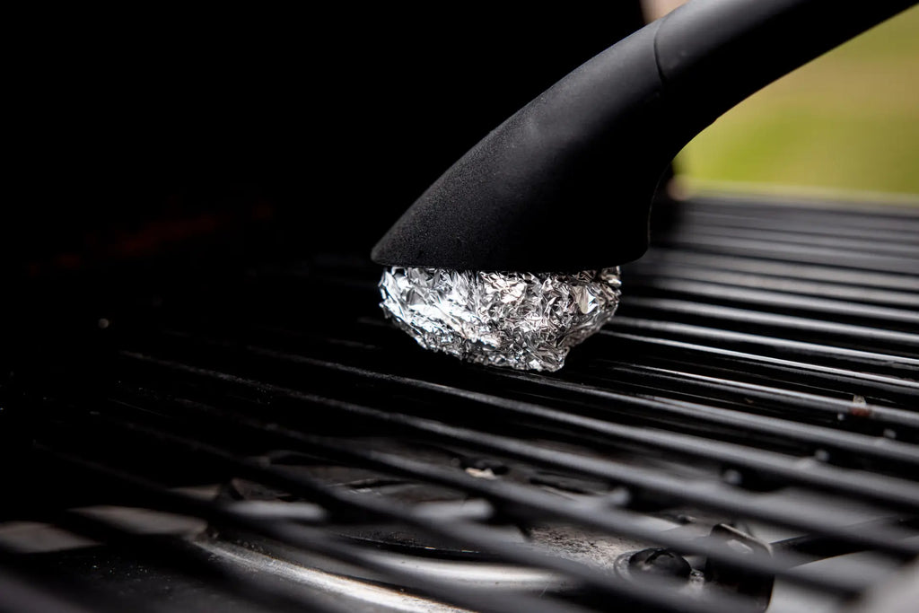 Using a specialized HALO handle to clean grill grates with crumpled foil for a deep-clean finish.