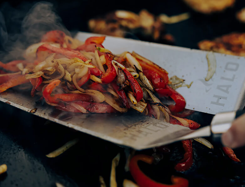 Grilled vegetables on a metal spatula with 'HALO' branding.