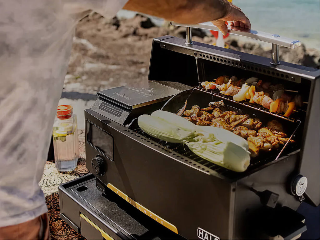 Person grilling vegetables on a portable grill outdoors.