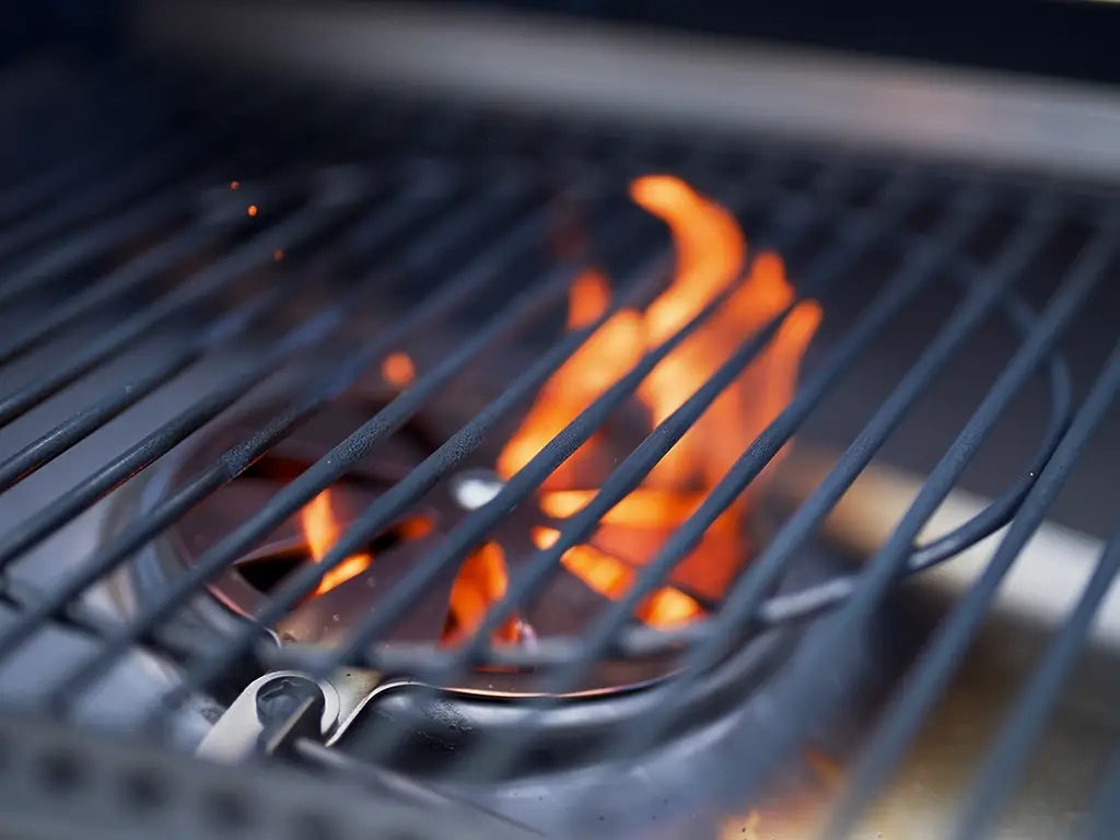Close-up of a HALO grill with high-performance burners and active orange flames through the grates.