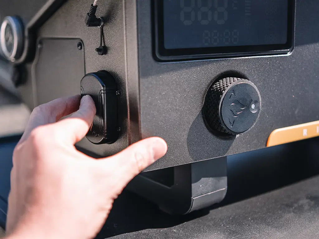 Hand adjusting the settings on a HALO pellet grill