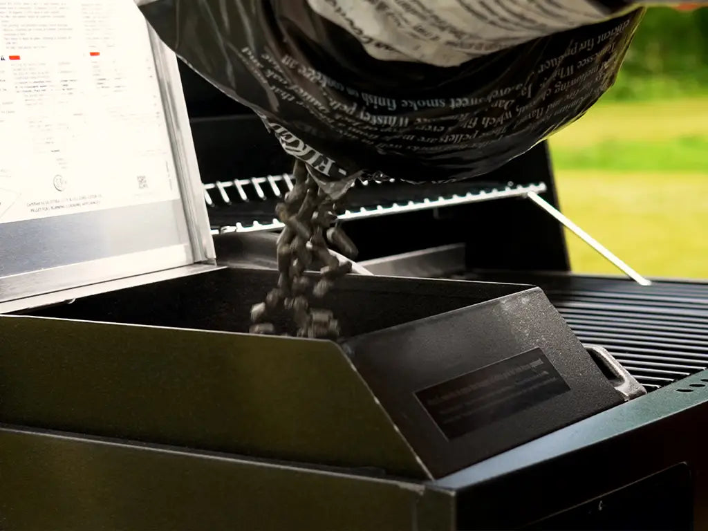Pouring wood pellets from a bag into the large hopper of a HALO pellet grill