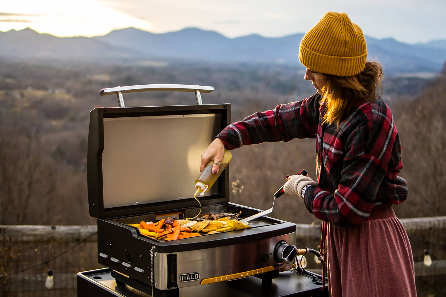 Woman grilling vegetables on HALO Elite1B, using the HALO squeeze bottle to dispense oil on the griddle.